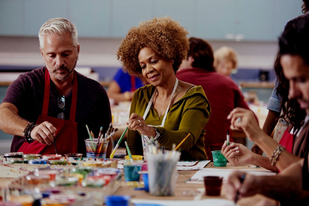 Older adults painting with brushes in a community class