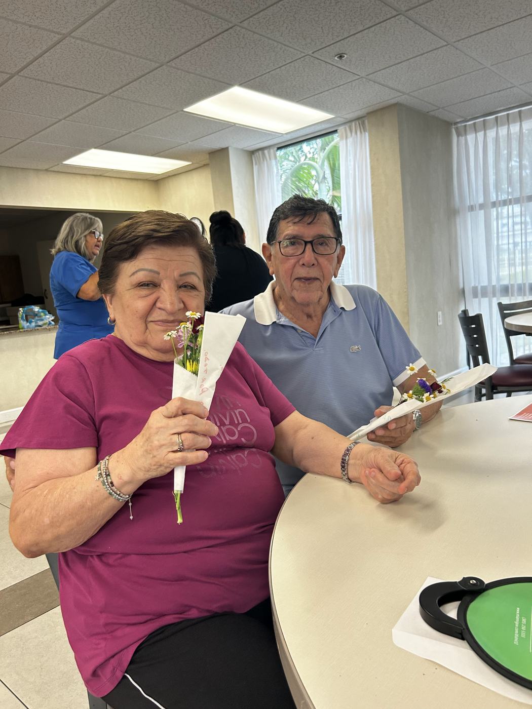 Two seniors holding a bouquet and card they made