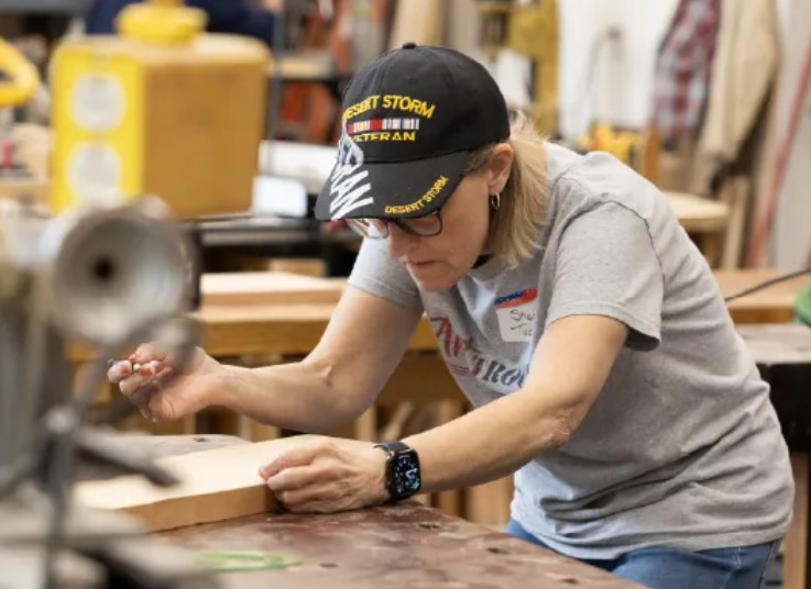A Desert Storm veteran carefully marking a piece of wood during a hands-on art workshop