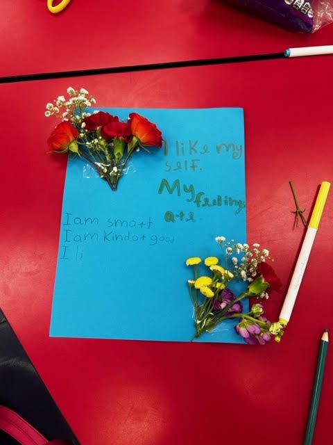 A student's blue card reading I like myself, I am smart, I am kind, decorated with roses